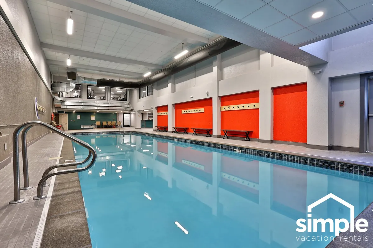This image features an inviting indoor swimming pool with bright red accent walls and a comfortable poolside seating area. It exudes a rejuvenating atmosphere, perfect for taking a refreshing break from work or engaging in leisure activities between meetings.