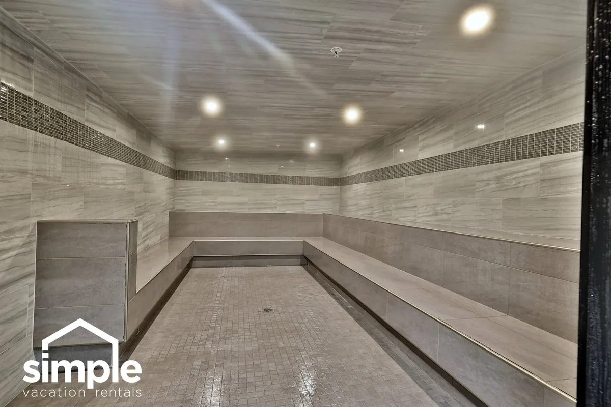 A serene wellness area with smooth benches, marble-like walls, and calming ceiling lights. The scene suggests a tranquil environment for relaxation, wellness treatments, and social gatherings centered around rejuvenation.
