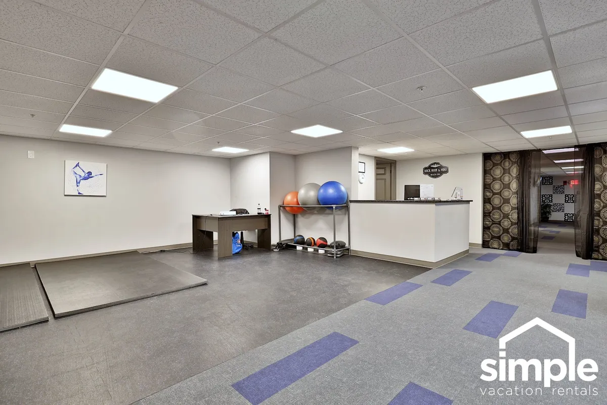 A vibrant fitness center is depicted, showcasing exercise mats, various fitness equipment, and a reception desk. The scene conveys personal training, group fitness classes, and wellness consultations, representing opportunities for health and movement during remote stays.