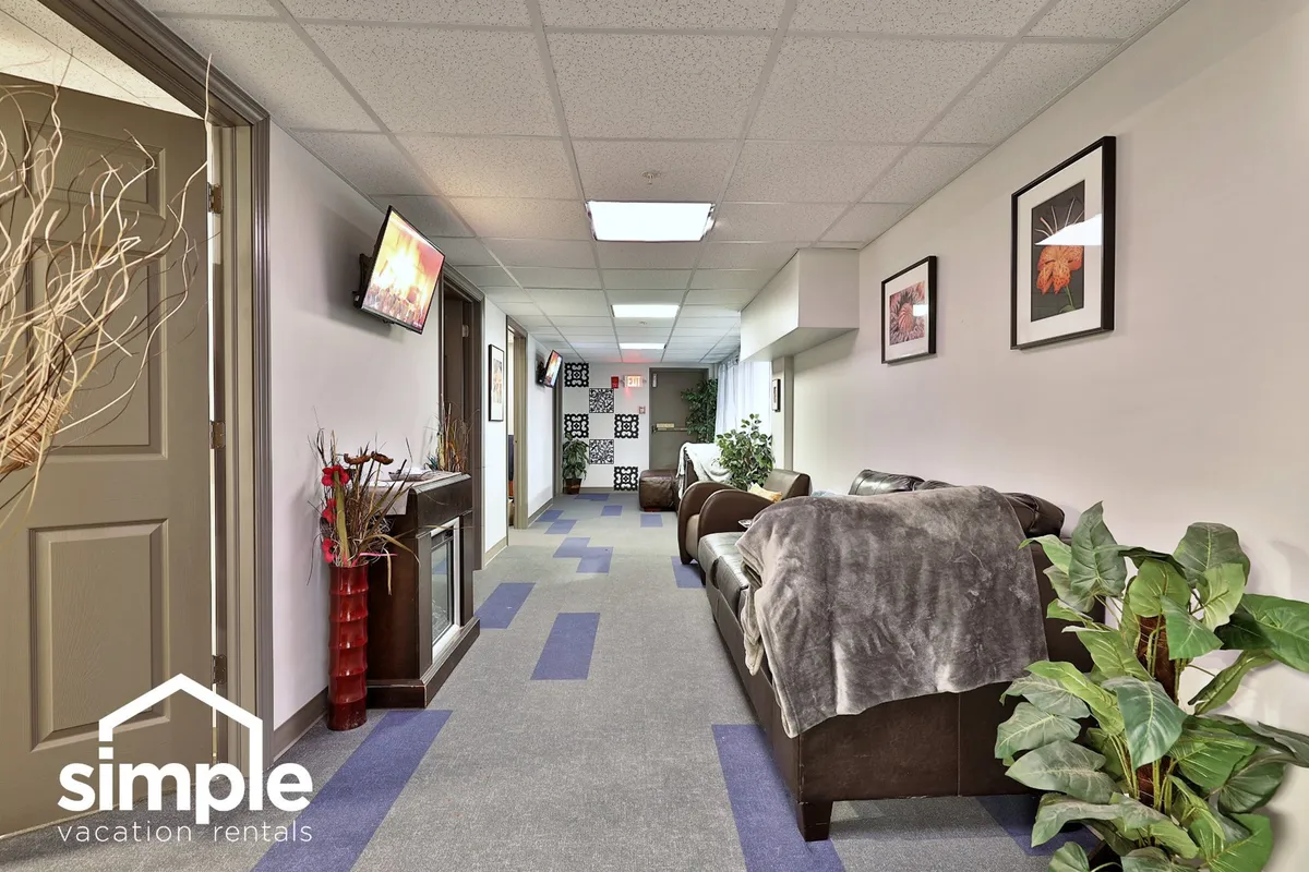 A cozy interior living space featuring a sofa, decorative plants, wall art, and a television, creating a relaxed and communal area for guests to unwind after outdoor adventures.