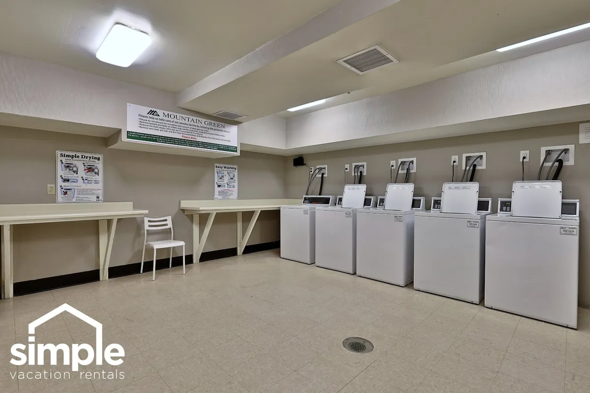 The shared laundry room is shown with multiple washing machines, folding tables, and informational signage, all in a practical and relaxed setting. It suggests convenience for extended stays and the ease of handling chores even on work trips.